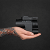 Tattooed hand holding Velectr NACS to CCS1 adapter showing compact design